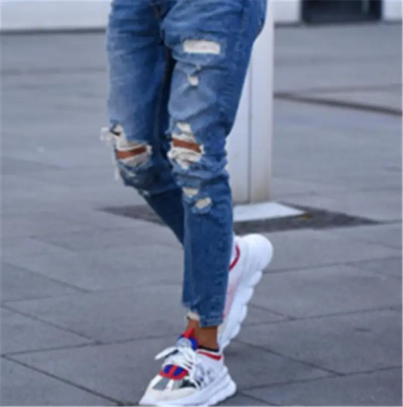 men’s distressed blue denim ripped knee jeans featuring frayed edges and distressed patches on blue ripped denim material