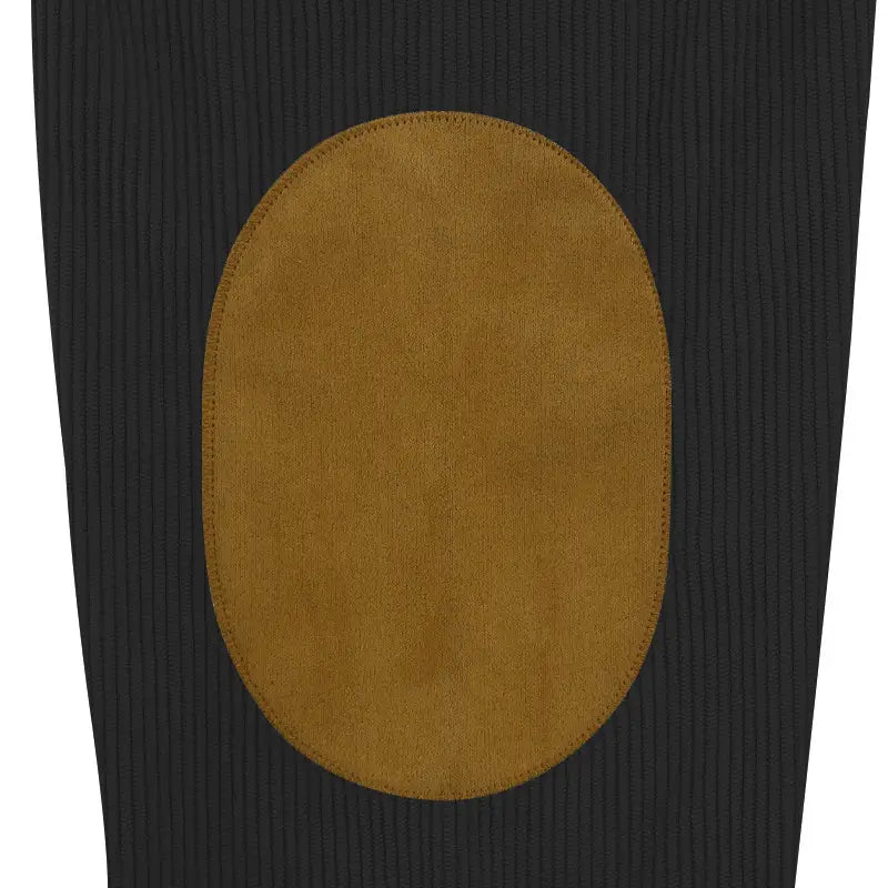 A tan suede elbow patch sewn onto a black ribbed fabric of a slim fit corduroy patchwork pullover with contrast accents.