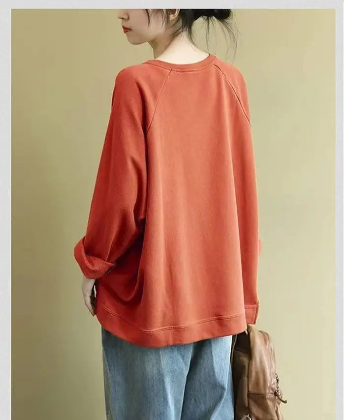 Women’s relaxed oversized cotton blend pullover sweatshirt in soft rust orange with a long-sleeved relaxed fit and ribbed cuffs.