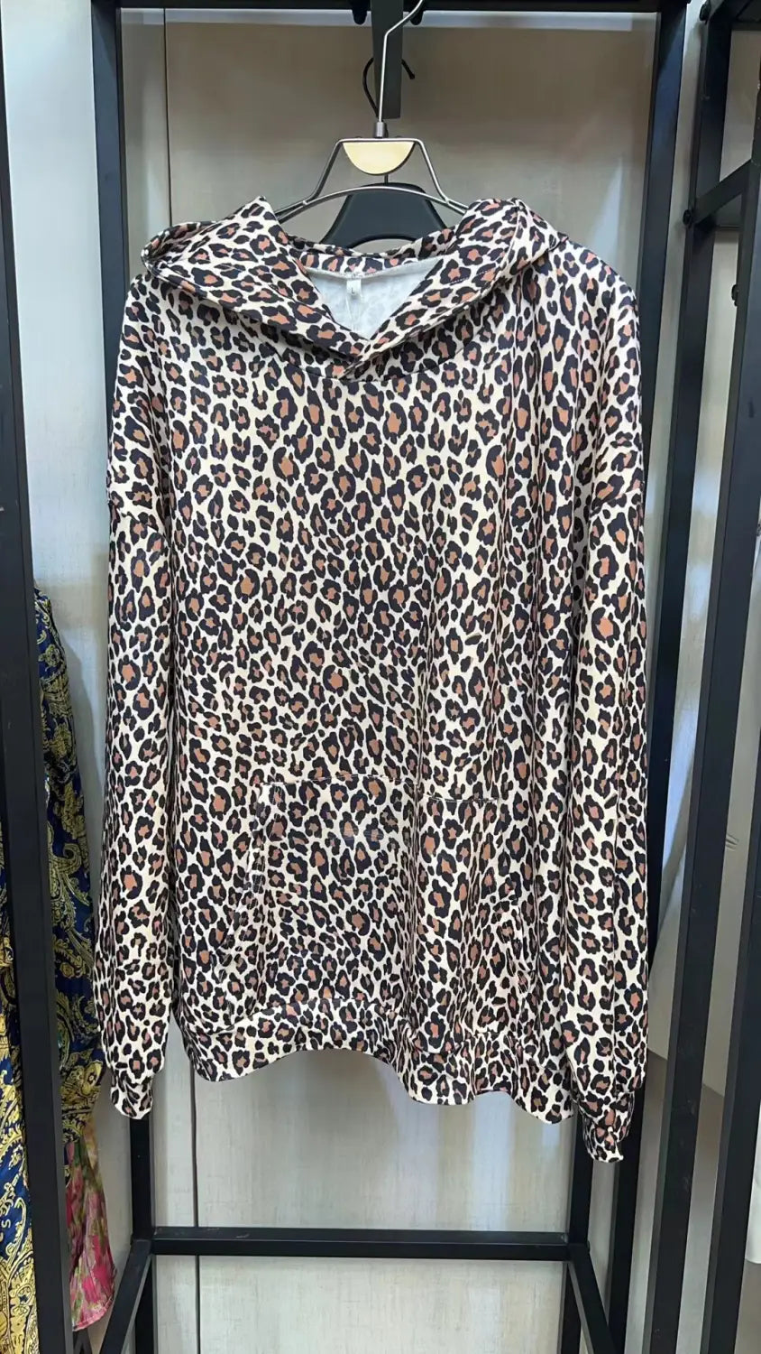 Ein beiges und braunes Leopardenmuster-übergroßes American-Vintage-Sweatshirt mit Kapuze, mit langen Ärmeln, das an einem schwarzen Kleiderbügel hängt.