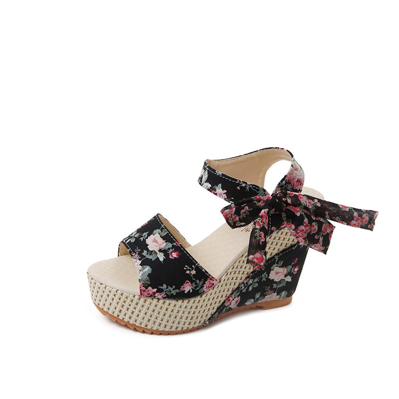 Black floral wedge sandal with woven beige platform and ankle strap tied in a bow from the floral bohemian platform wedge sandals with ankle ties collection.