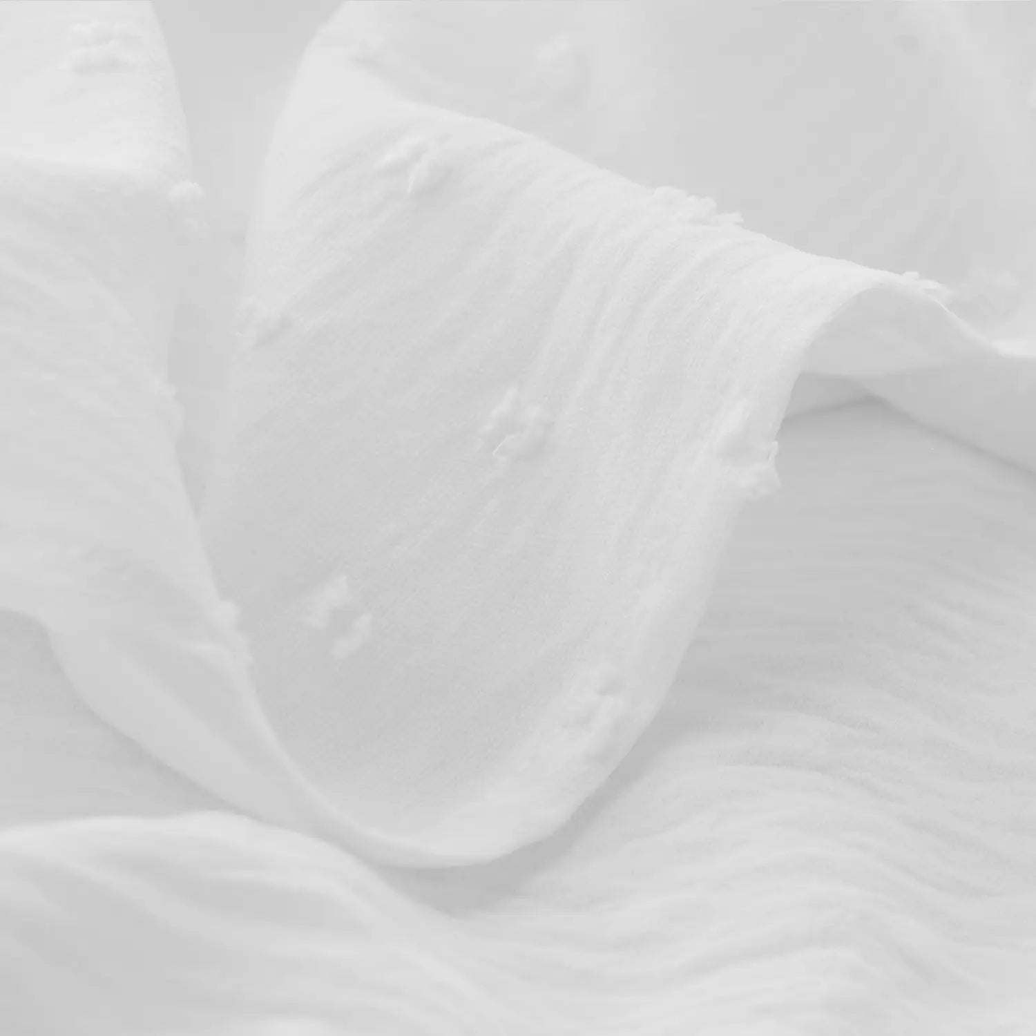 soft flowing white fabric with gentle folds and subtle texture on off shoulder long sleeve ruffled tiered mini dress