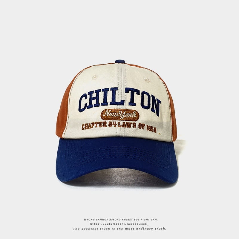 Casquette de baseball rétro à empiècements contrastés crème et orange, avec visière bleu marine, portant une broderie « Chilton » en lettres bleues foncées en caractères gras au-dessus d’un écusson ovale brun indiquant « New York Chapter 84 Laws of 1950 ».