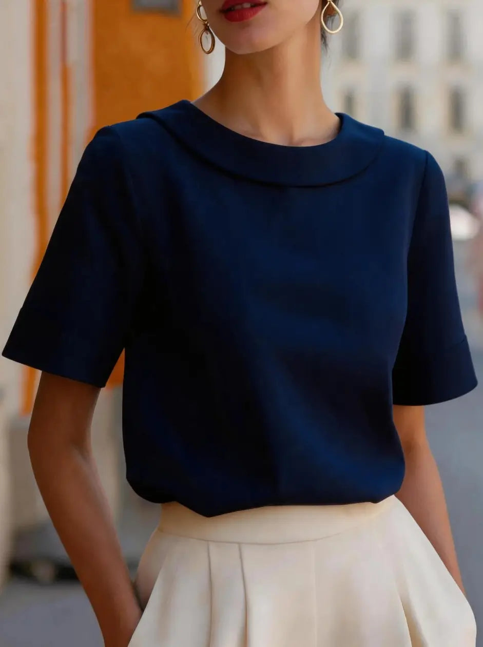 Navy blue short-sleeved blouse with rounded neckline made of soft structured fabric for versatile women’s wear.