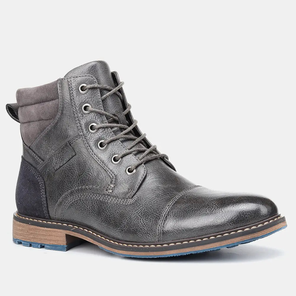 Men’s leather martin boot in dark gray with contrasting suede collar and navy blue panel featuring silver eyelets tan stitching and blue rubber sole.