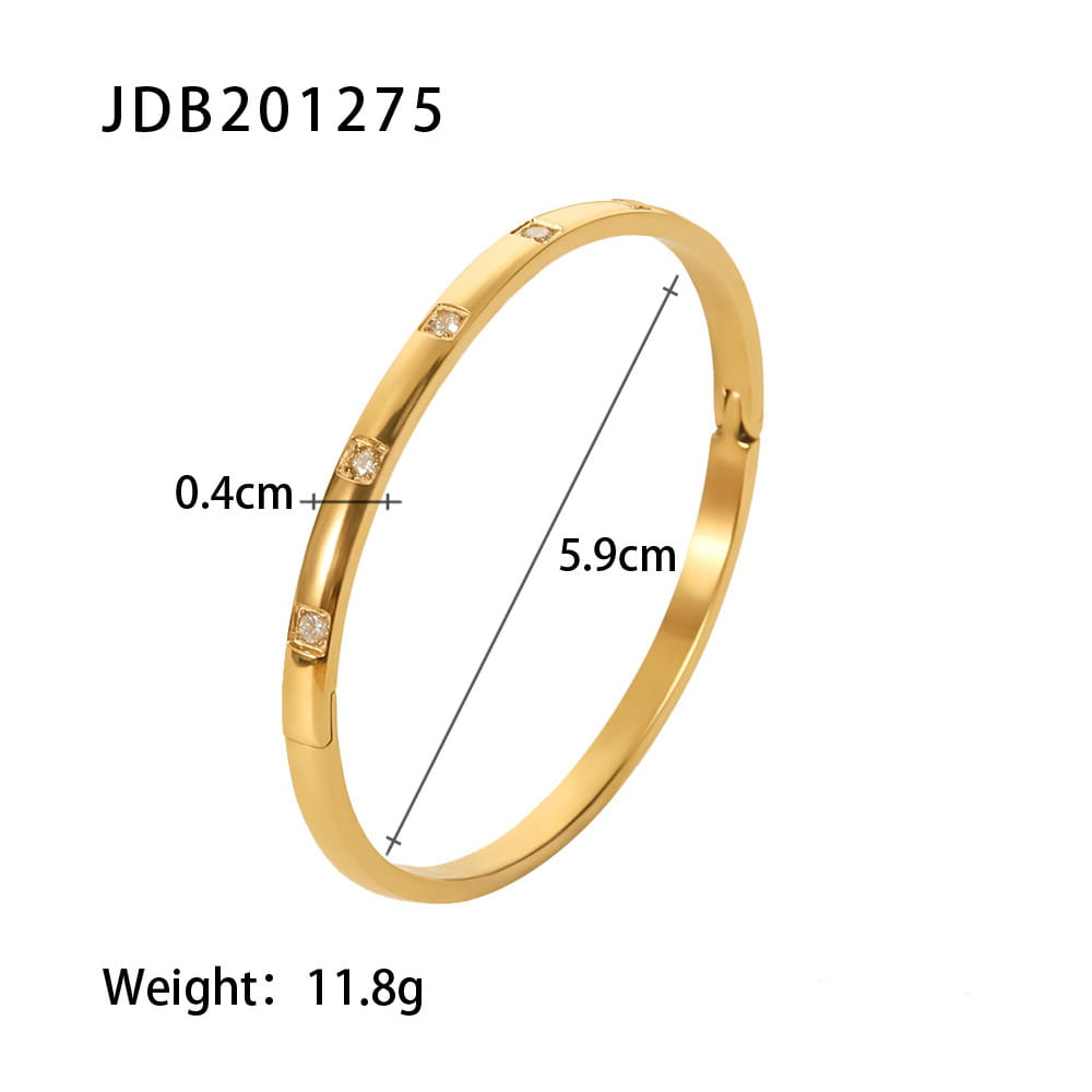 Gold plated stainless steel bangle bracelet in gold tone featuring four square-cut clear zirconia gemstones set along its inner curve.