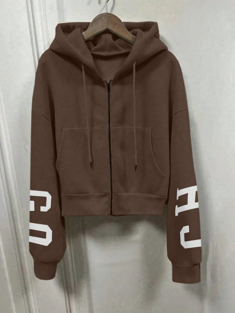 Hoodie zippé marron court avec lettrage blanc sur les manches, présentant un design d’impression graphique.