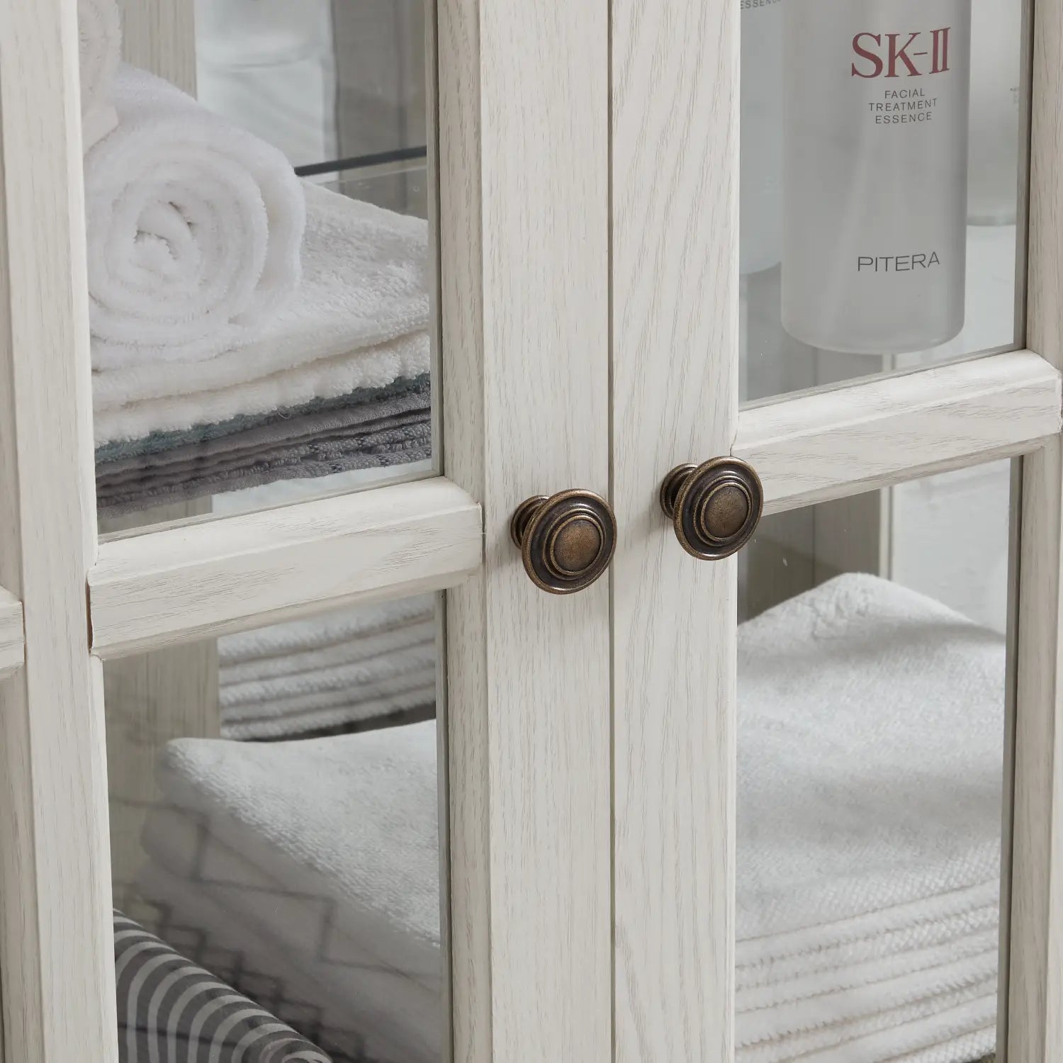 led curio display cabinet with lattice doors in white distressed wood featuring bronze round knobs.