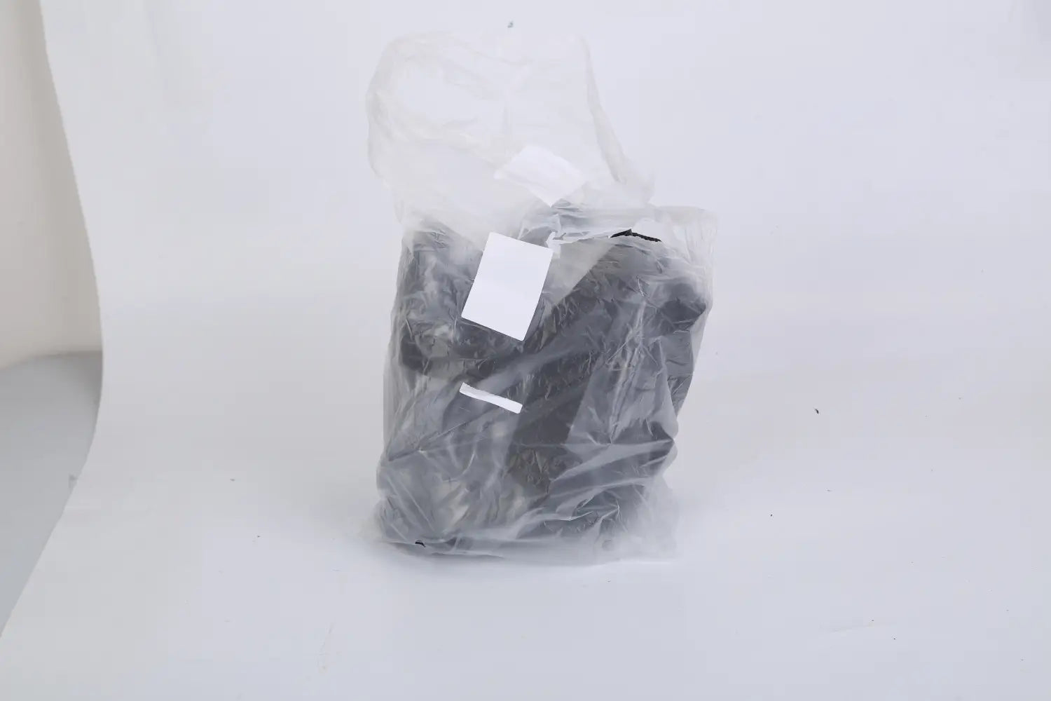 A black plastic bag containing a bundled item for the stadium approved clear crossbody bag with mesh pockets.