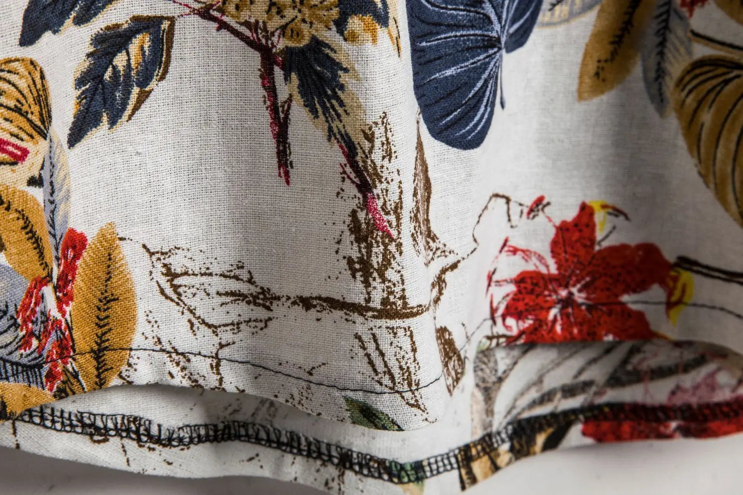men slim fit tropical floral short sleeve button shirt in white fabric with vibrant red flowers blue leaves and golden foliage in a detailed botanical print.