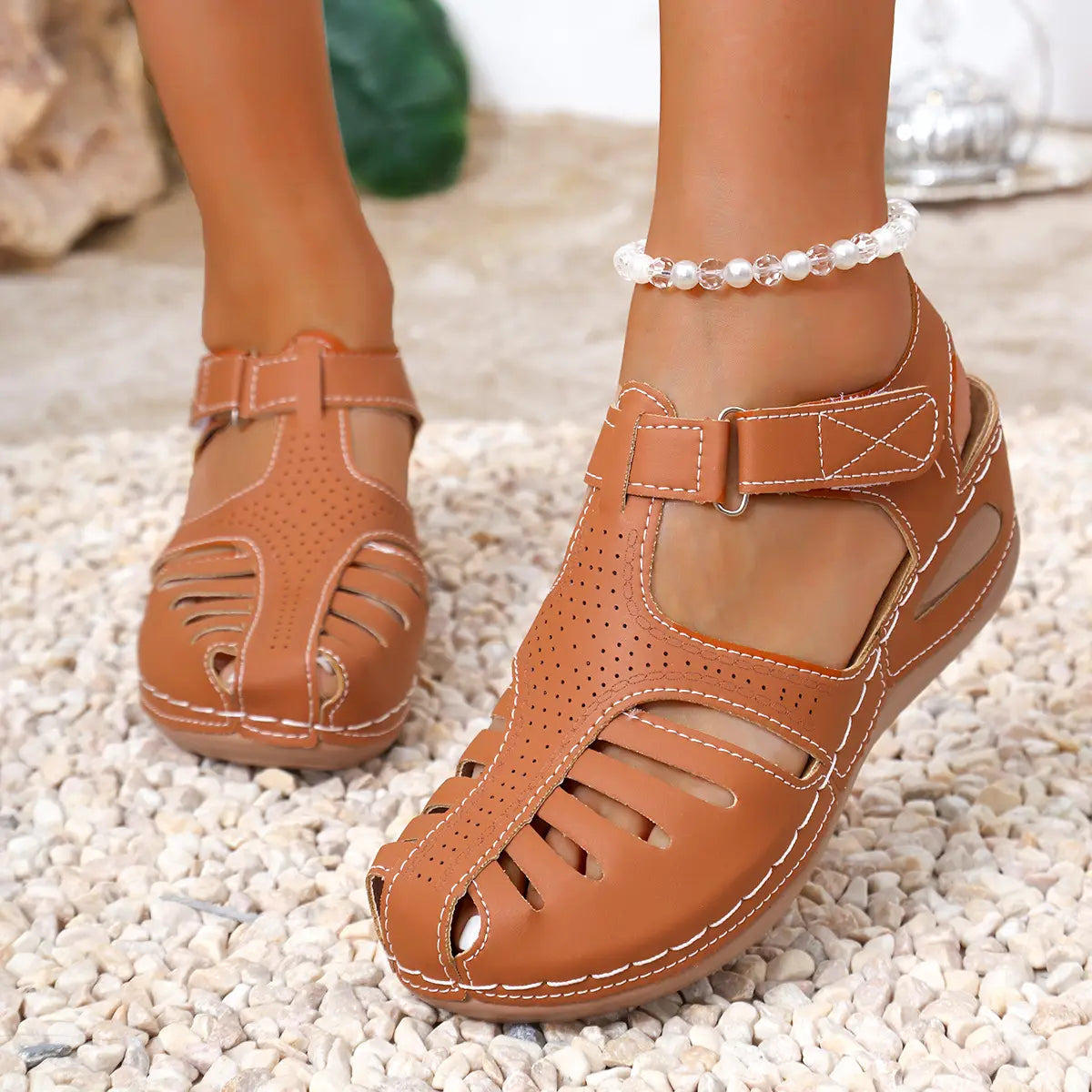 Sandales compensées pour femmes en cuir beige, avec détails perforés et surpiqûres blanches, conçues pour une tenue estivale au style romain.