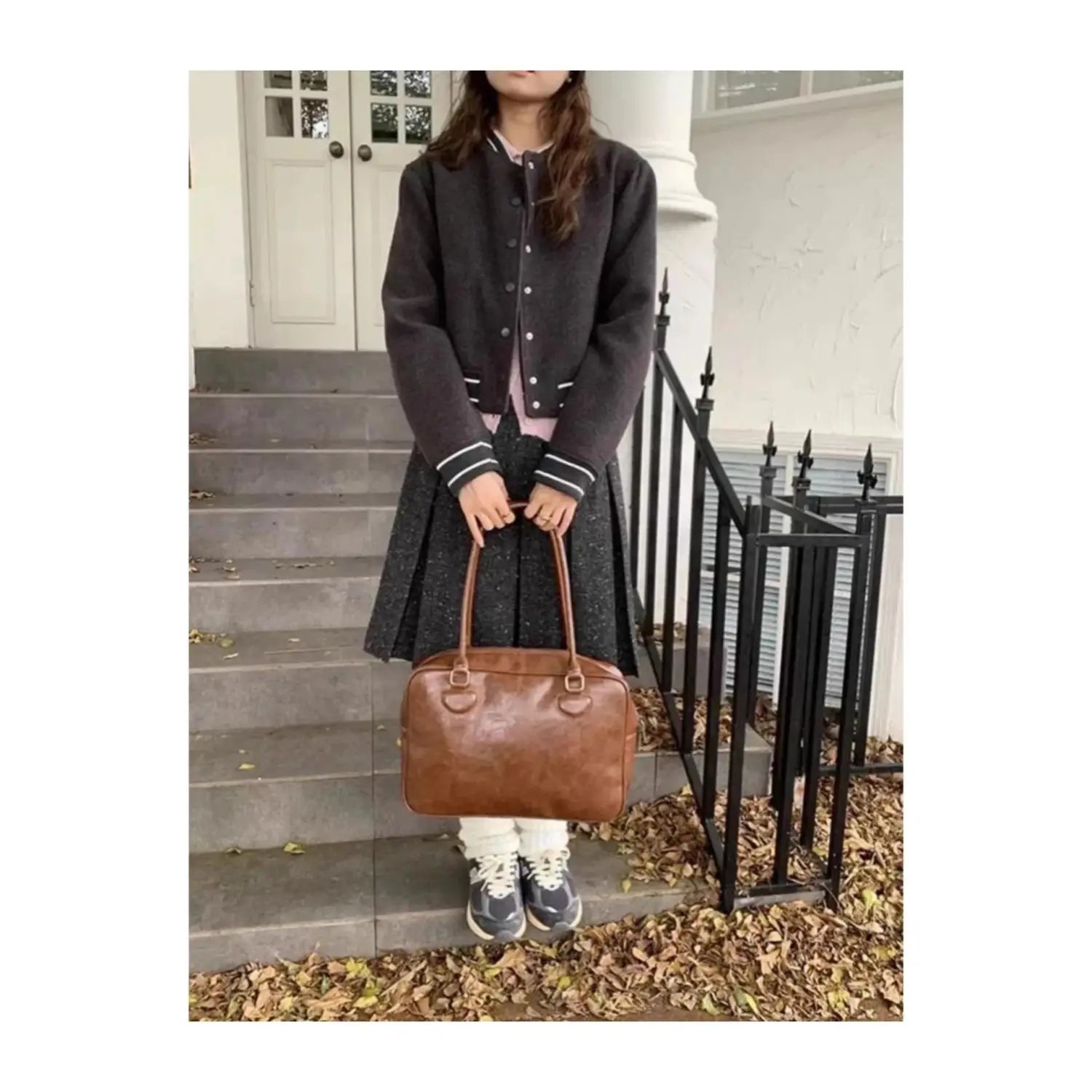 Brown leather handbag with top handles and a structured rectangular shape featuring a large capacity and bear charm suitable for shoulder use.
