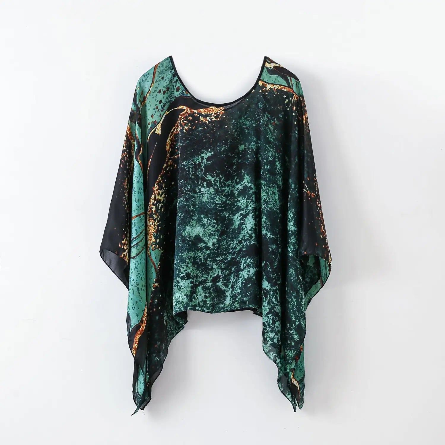A flowing cape-style printed silk patterned pullover shawl cape outerwear in vibrant green and black marble print with gold accents.