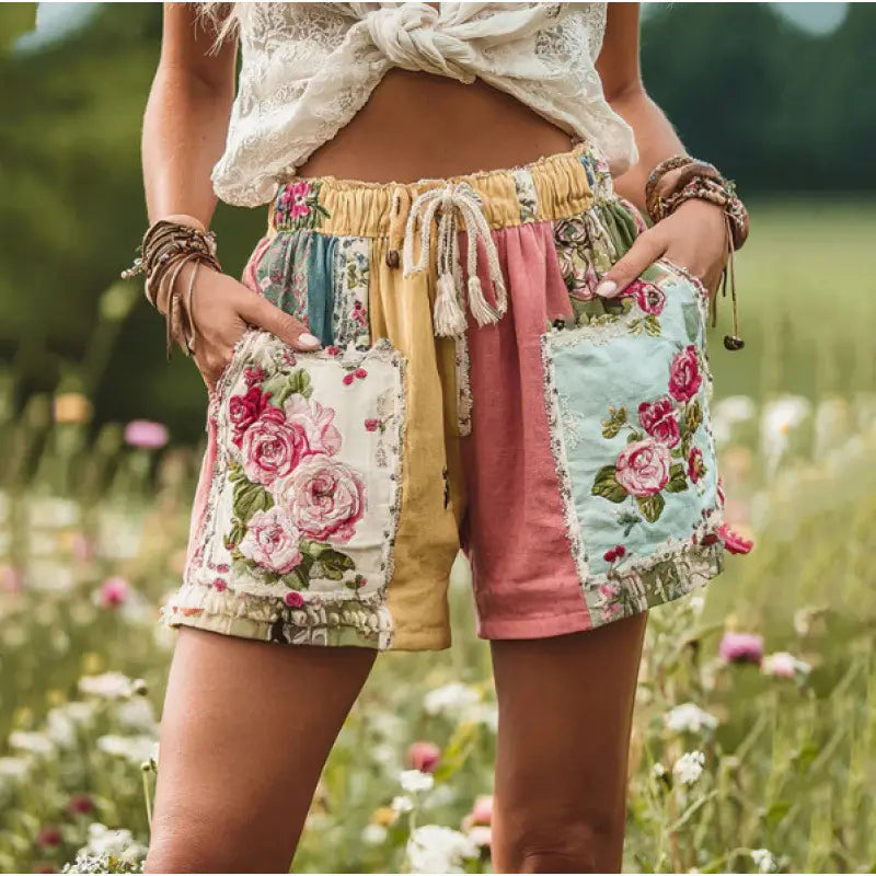 やわらかなパステル調の花柄パッチワークのカジュアルショートパンツ。ポケットには花の刺繍が施され、ドローストリングのウエストとほつれたエッジを備えています。