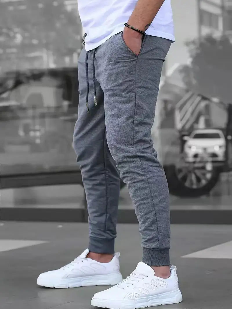 Herren-Frottee-Jogginghose in Grau mit Kordelzug am Bund und gerippten Bündchen, entworfen für den Casual-Streetwear-Stil.