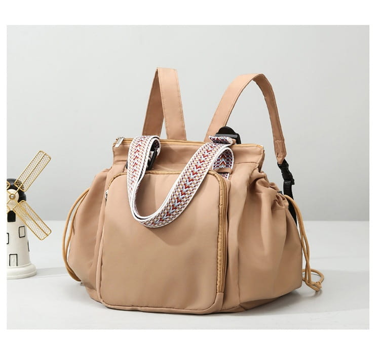 Beige nylon multifunctional waterproof fashion tote and backpack with a woven strap featuring a red and white geometric pattern.