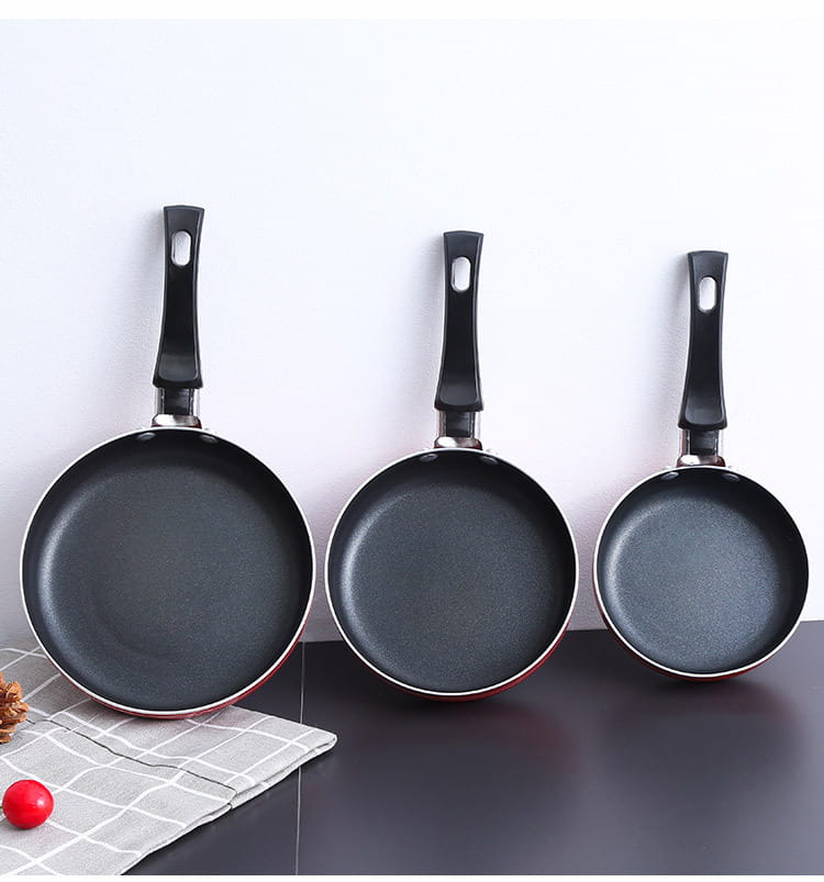 Set of three black mini non-stick frying pans with red rims and ergonomic handles made of aluminum cookware.