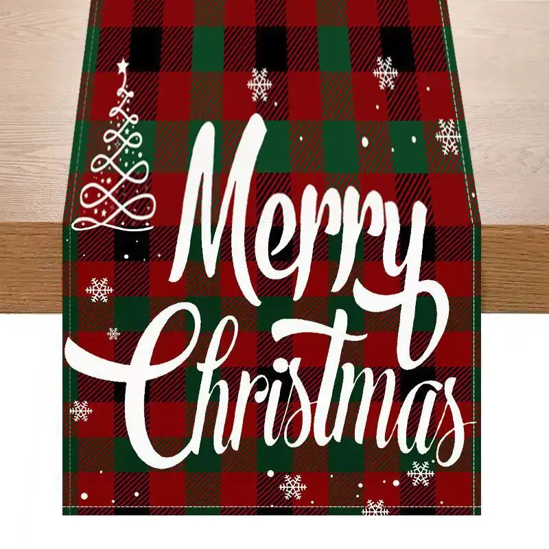 Red and green plaid Christmas table runner measuring 183 by 33 inches featuring white merry Christmas script, snowflakes, and a stylized tree design for festive holiday decor.