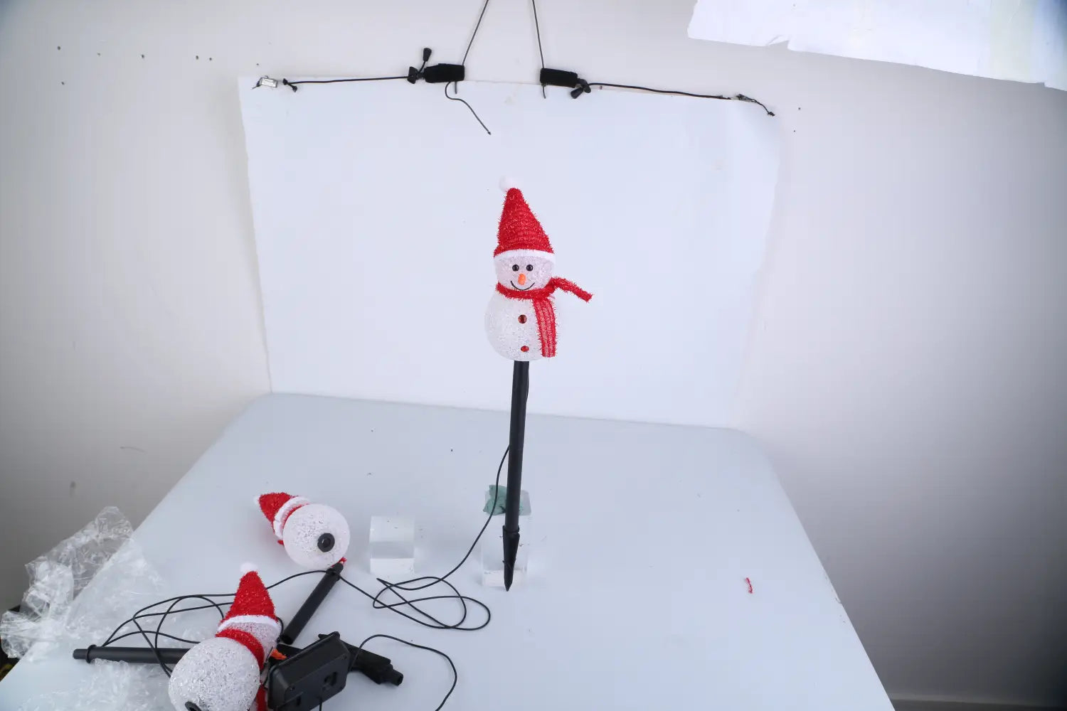 Un brise-soleil de jardin solaire en forme de bonhomme de neige en tricot rouge et blanc, avec un piquet noir et une classification d’étanchéité IP55.