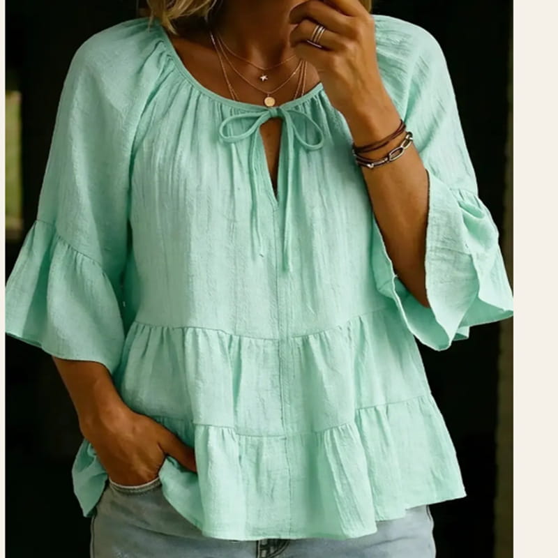 Blusa de algodón y lino color verde menta, plisada, con diseño en niveles, mangas con volantes y escote con lazo al frente.