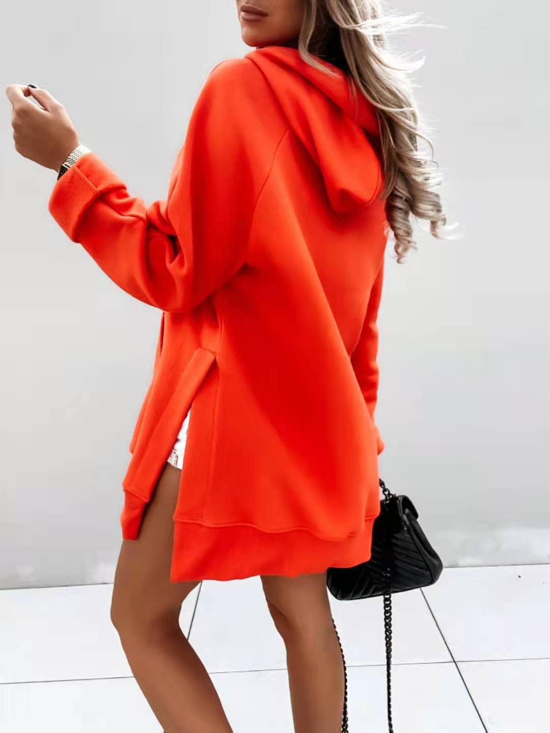 vibrant orange oversized mid length hooded sweatshirt dress made of soft fabric featuring a hood and side slits with pockets for casual wear