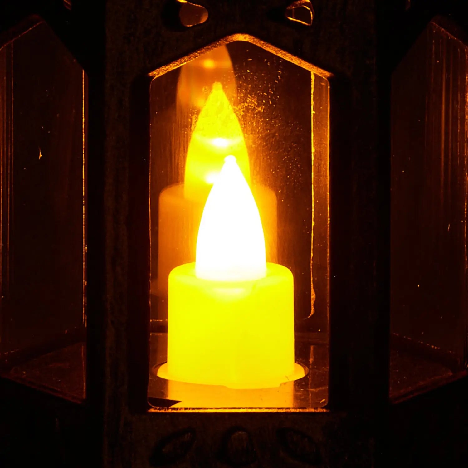 a glowing yellow led candle with a realistic flame effect inside a dark bronze five inch decorative lantern from a 12 pcs led candle lantern set