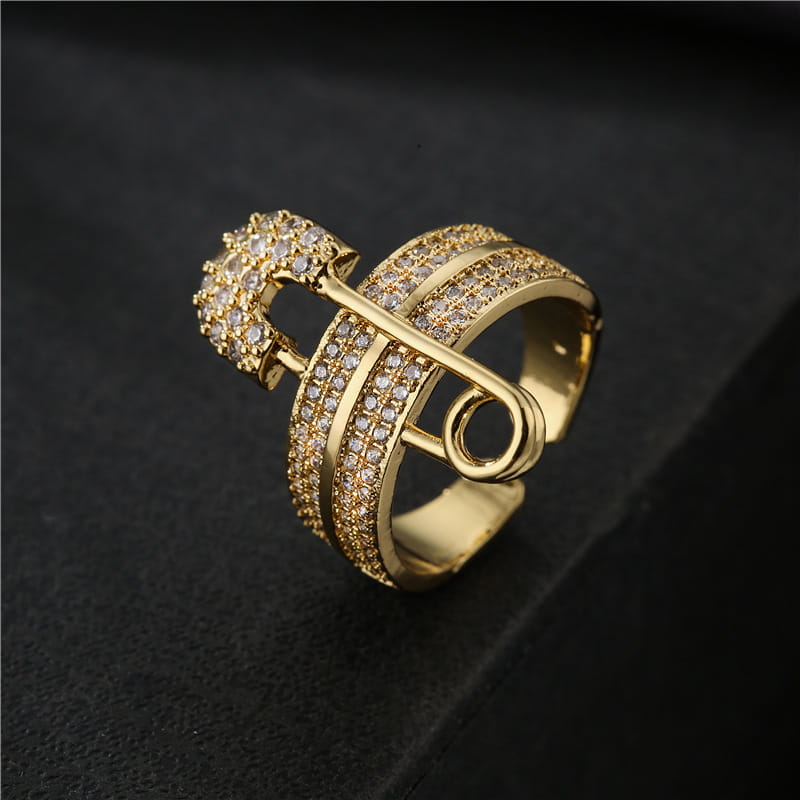 Adjustable gold safety pin ring featuring numerous clear sparkling cubic zirconia stones in a geometric design.