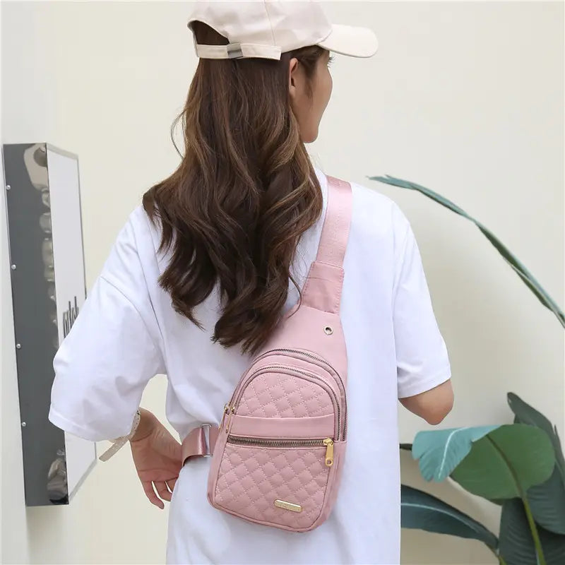 Pink quilted crossbody slanted chest bag for women with gold-tone zippers and matching strap made of soft leather material.
