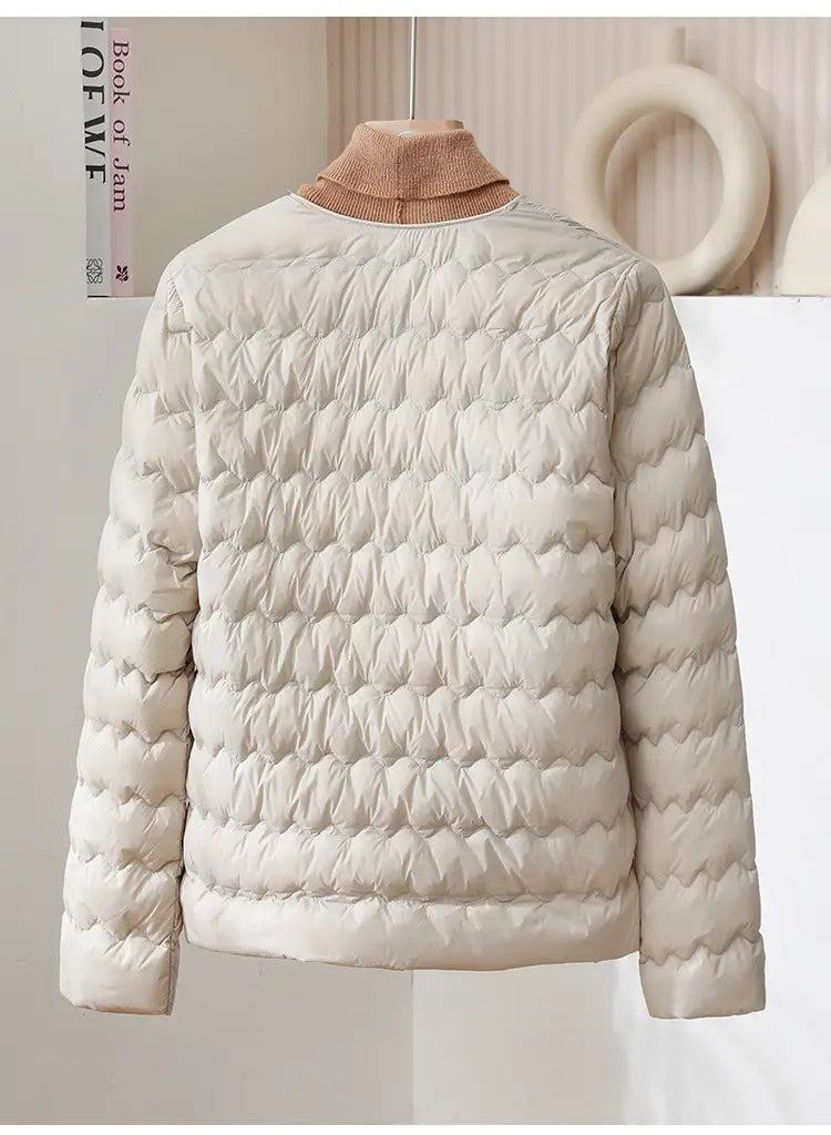 Cream-colored quilted puffer jacket with a soft beige turtleneck collar featuring a ruffled crew neck design.