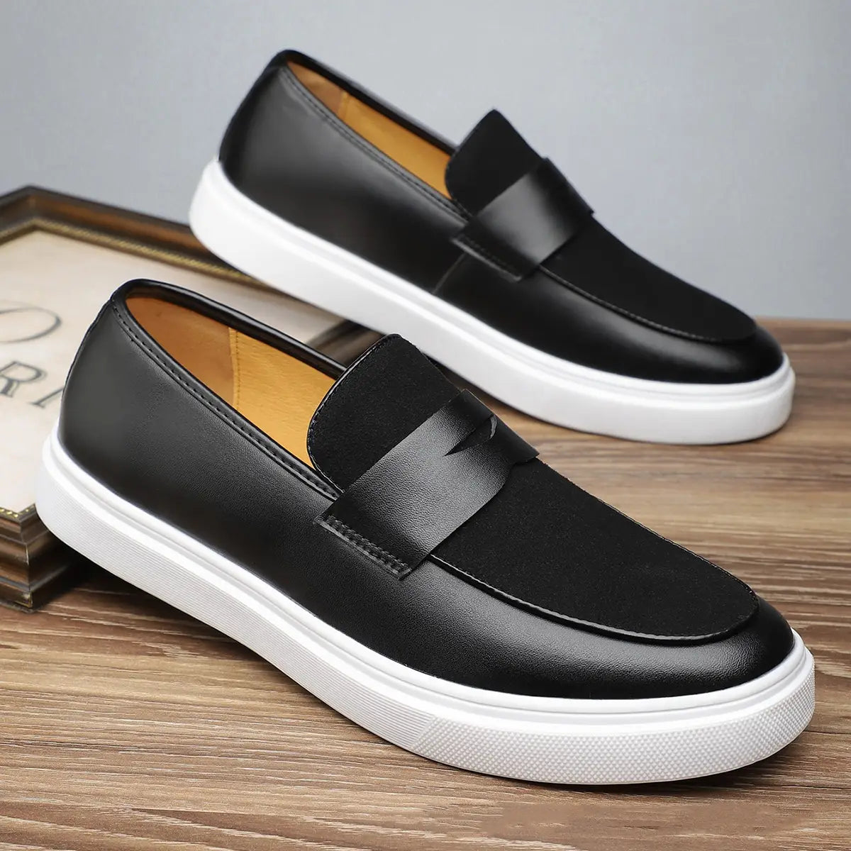 Herren-Leder-Slipper zum Hineinschlüpfen in Schwarz mit weißer Gummisohle und kontrastierender hellbrauner Innenfutterauskleidung, sichtbar aus der Seitenansicht