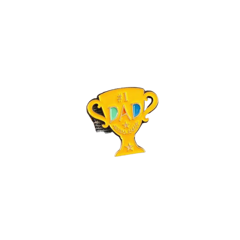A shiny gold enamel #1 dad trophy pin with colorful letters and stars on denim fabric