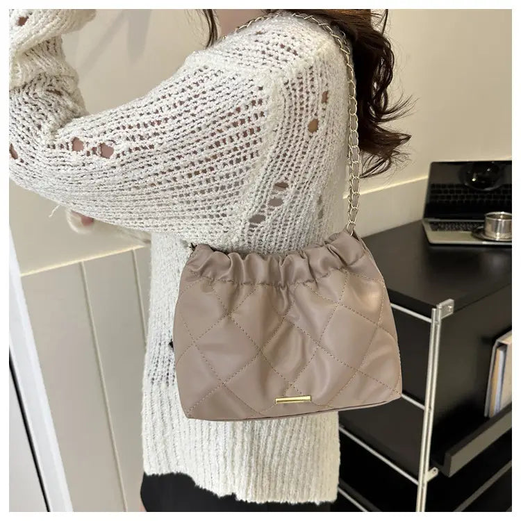 Beige quilted faux leather crossbody bag with a chain strap and gold tone hardware.