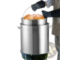 Stainless steel 100qt stockpot with perforated strainer basket and handle designed for outdoor turkey roasting