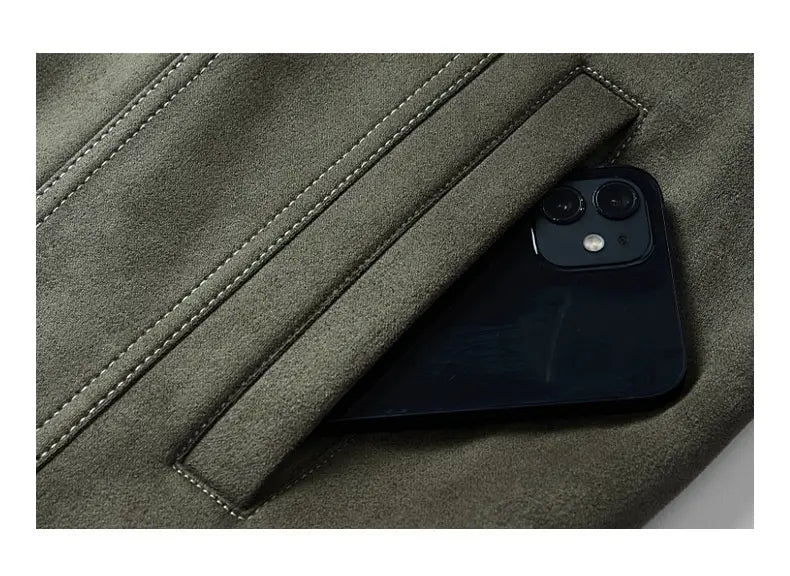 Un élégant iPhone noir équipé d’un système à double caméra repose, en partie, dans la poche en suède vert olive d’un manteau en suède décontracté ajusté pour homme.