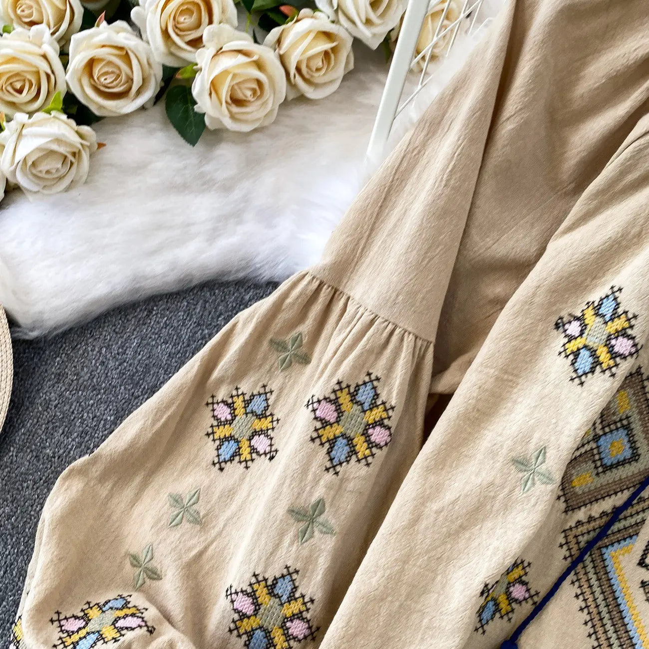 Beige embroidered lantern sleeve tie neck blouse featuring colorful geometric patterns and delicate star motifs.