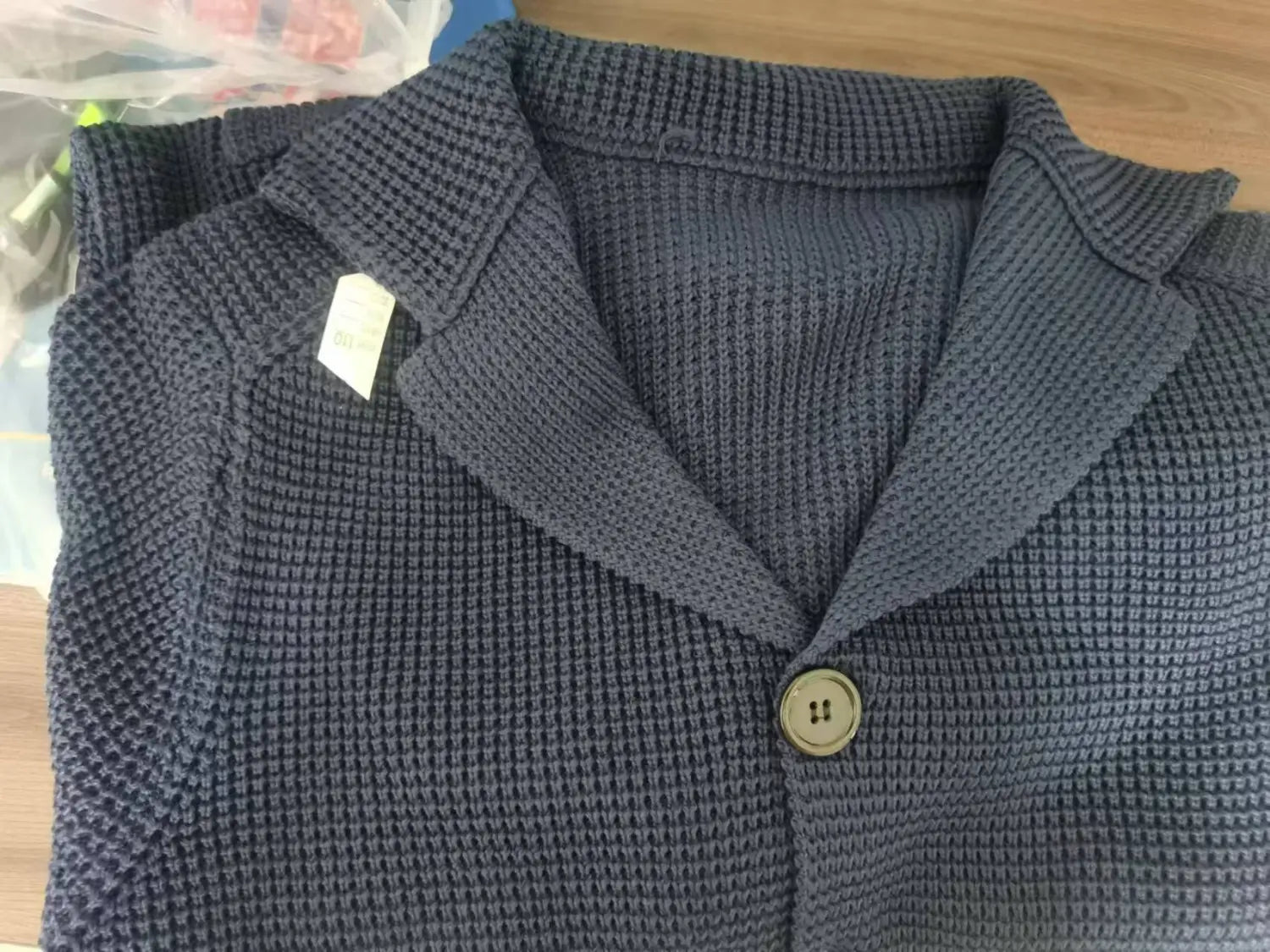 Cardigan tricoté gris foncé pour homme, avec texture façon gaufrée, fermeture à un bouton et col montant structuré.