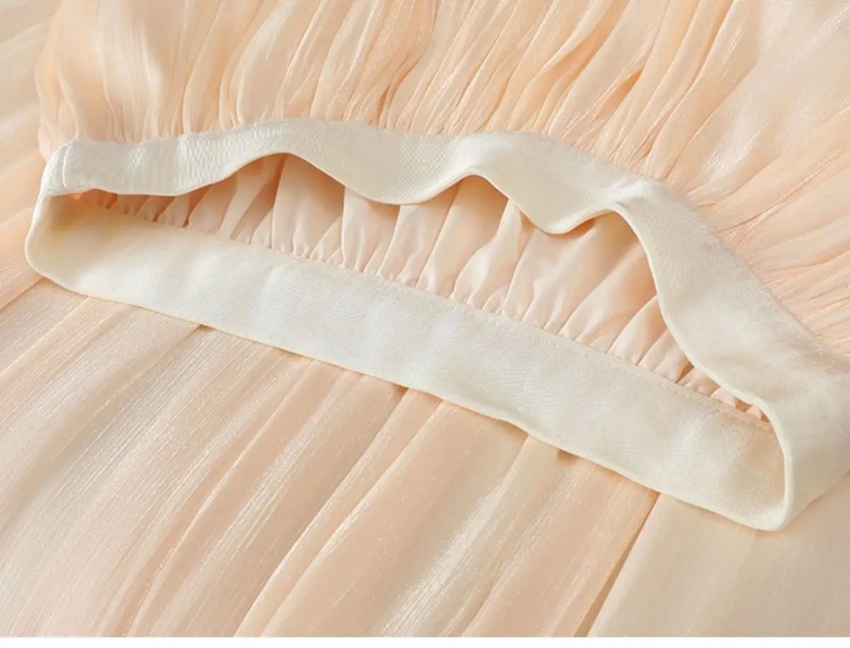 Ein sanftes pfirsichfarbenes, irrisierendes Chiffon-Faltenrock mit glattem cremefarbenem Satindbund.