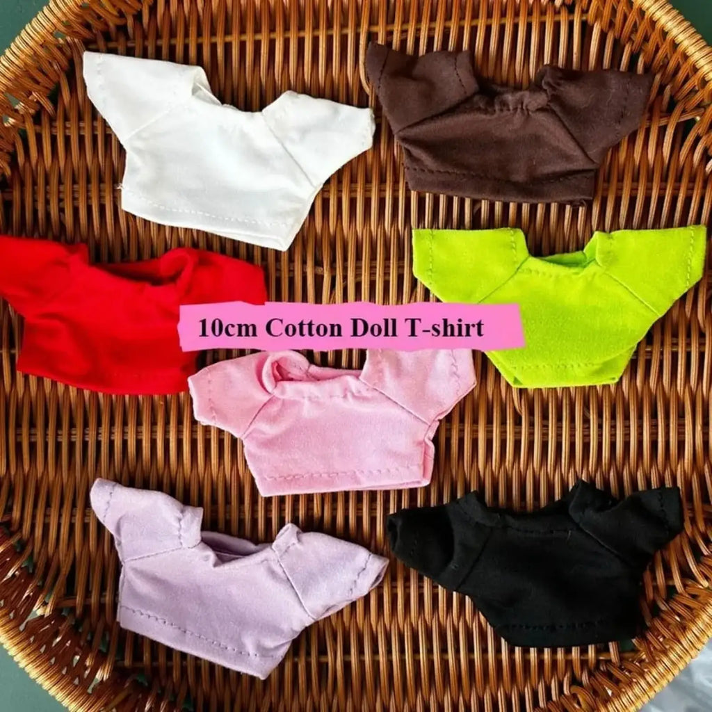 Six miniature cotton t-shirts in white brown red lime green pink and black on a woven wicker tray for 10cm dolls
