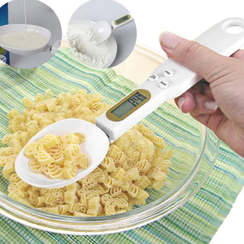 White digital spoon scale with gold-accented LCD display and buttons holding pasta in its bowl for precise kitchen measuring up to 500 grams.