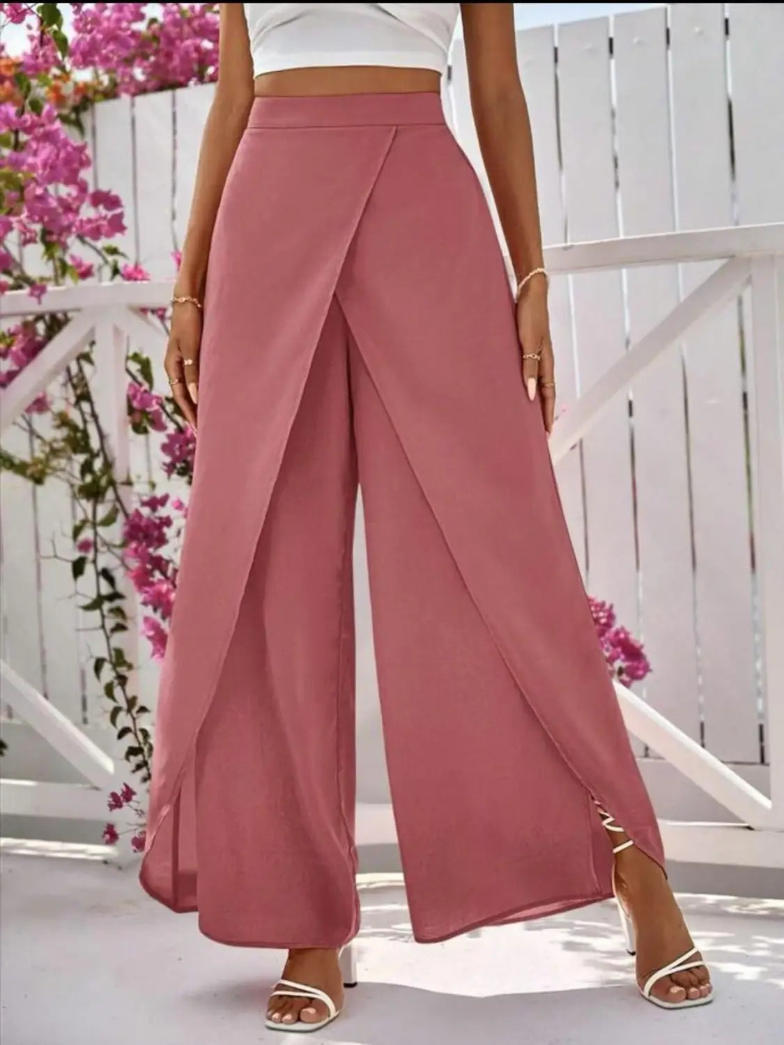 Ein Paar hoch taillierte, weite, rosafarbene Hosen mit Drapierungs-Frontdesign und seitlichem Schlitz, geeignet für den Casual-Bereich.
