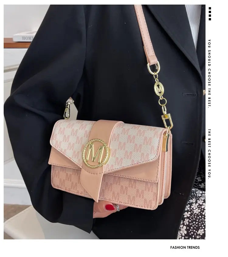 Pink monogram letter print crossbody messenger bag with repeating pattern and gold-tone logo clasp.