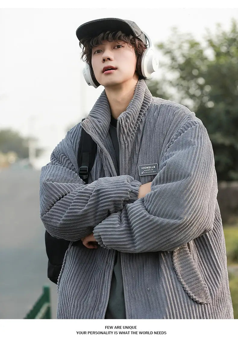 Herren Cord-Pufferjacke für den Winter als warmer Mantel in Grau mit gerippter Struktur und kleinem schwarzem Brustaufnäher.