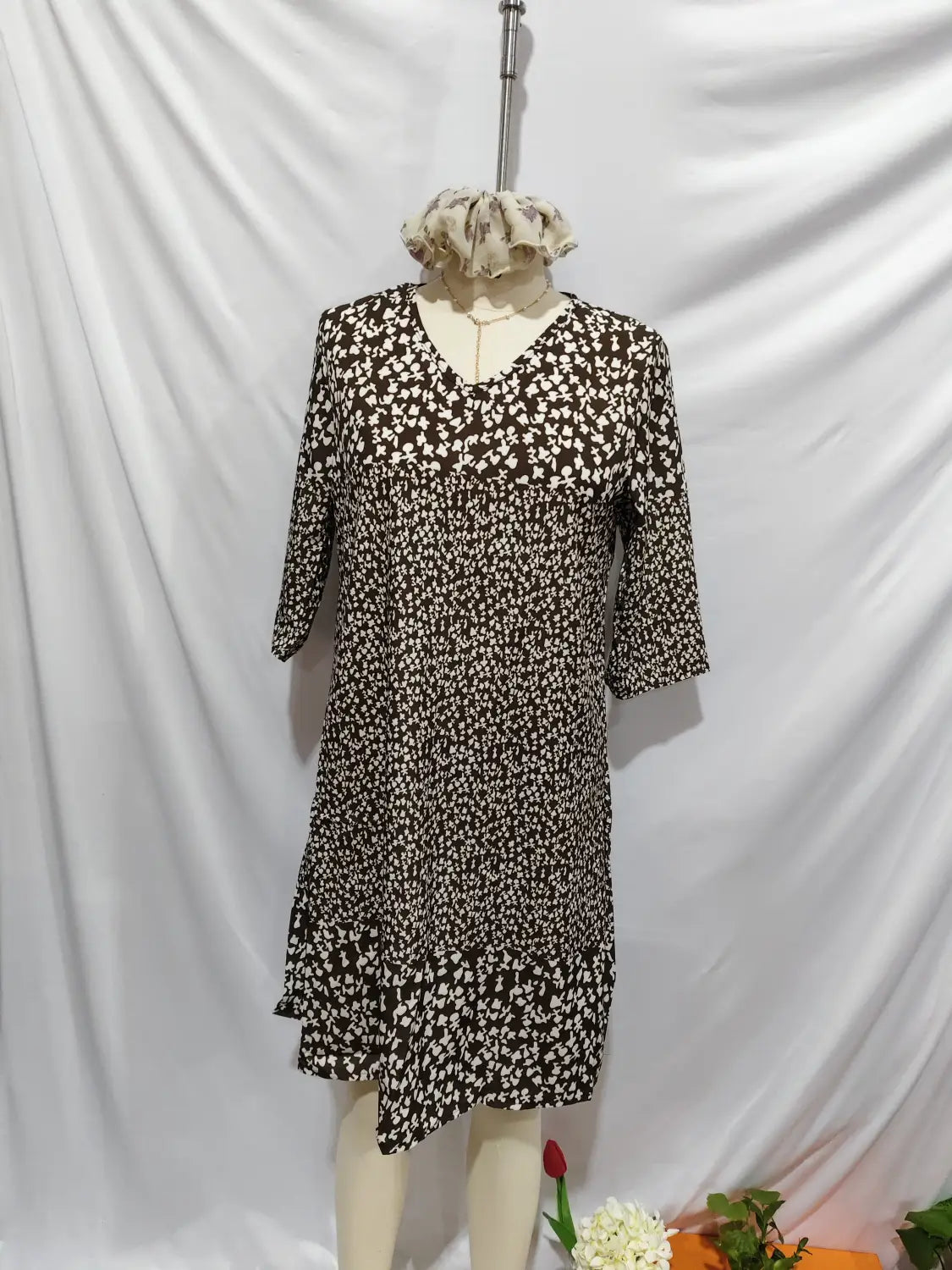 Une robe midi à imprimé floral noir et blanc, avec une encolure en V, des manches trois-quarts et un ourlet asymétrique.