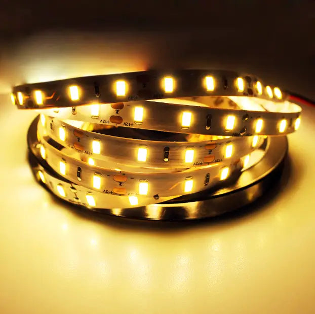 Coiled warm white LED strip lights with evenly spaced glowing bulbs on a flexible waterproof circuit board for home decor 5m.
