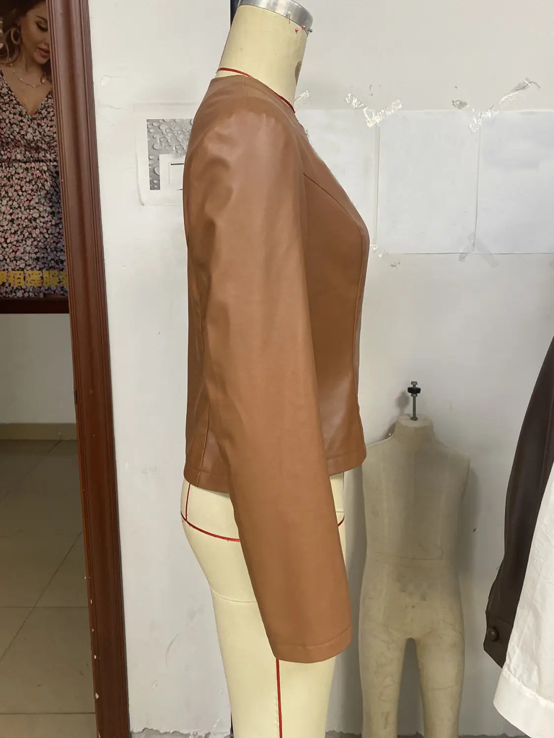 A tan faux leather cropped bomber jacket with long sleeves displayed on a mannequin for women’s outwear.