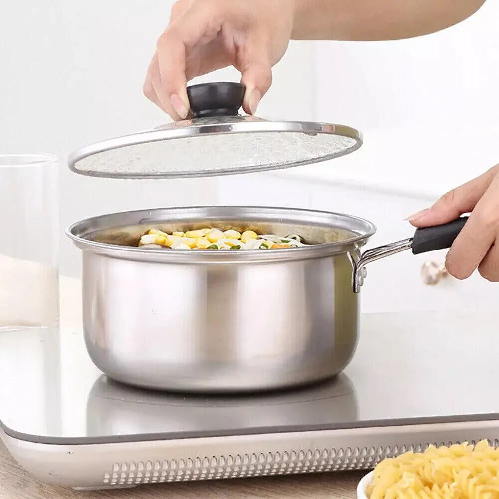 Cazo de acero inoxidable con asa negra y tapa de vidrio transparente de un juego de utensilios de cocina de acero inoxidable para inducción con tapas de vidrio.