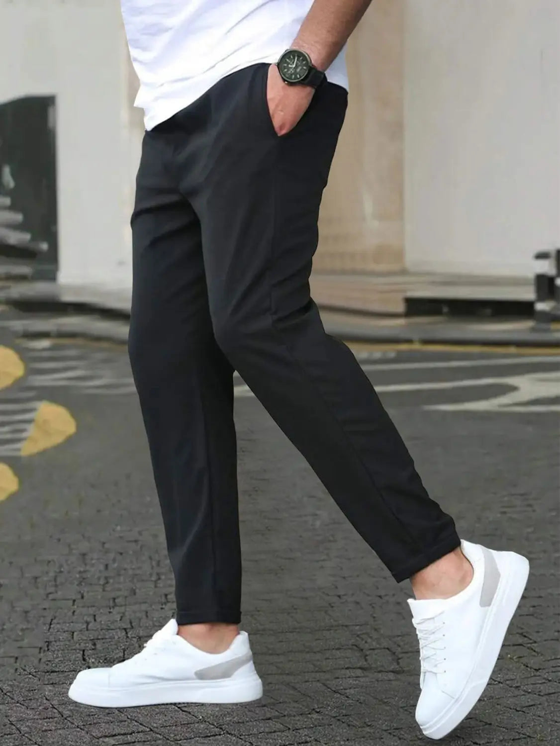 Black slim fit tapered jogger pants with subtle texture and drawstring worn with white sneakers.