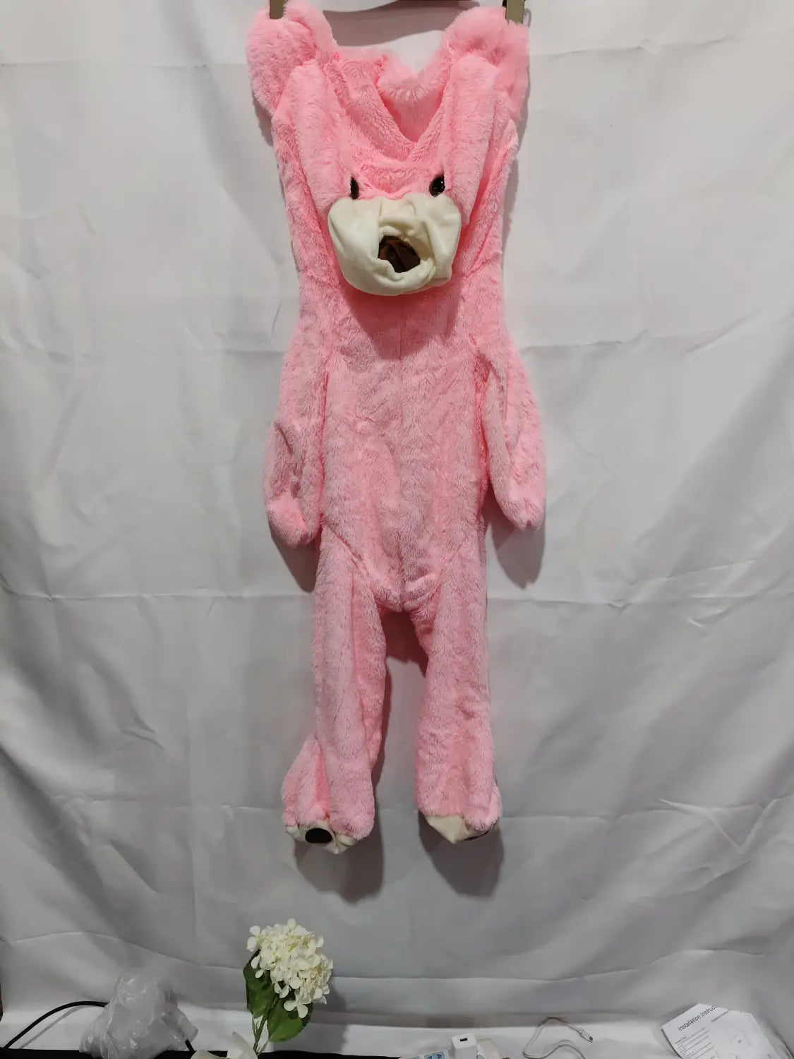 Pink plush giant teddy bear onesie with a white face and black eyes featuring an unfilled leather shell.