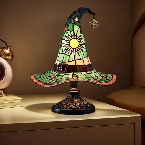 A green stained glass witch hat lamp with a yellow sunburst design star accents and a black belt detail for gothic Halloween decor.