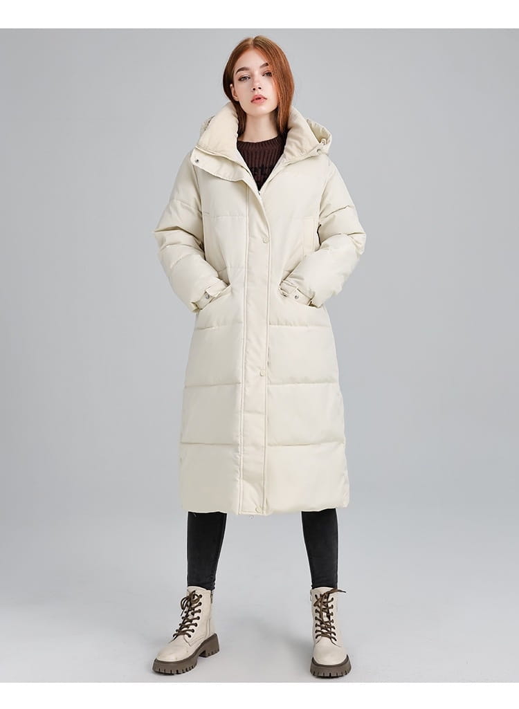Manteau long matelassé à capuche pour femmes de couleur crème, en doudoune matelassée, avec des poches avant pour la chaleur et le style.